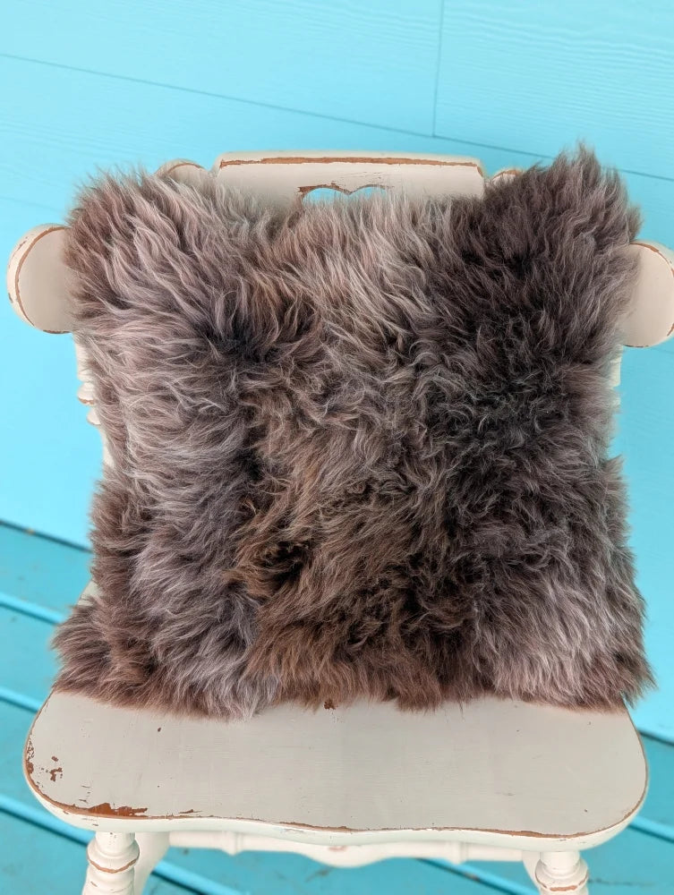Fluffy medium-length brown british sheepskin cushion with soft natural texture on unbleached cotton canvas angus oliver