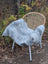 Gray faux fur throw draped over wicker chair with white metal legs featuring long wool Icelandic sheepskin texture