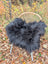 Black fluffy long wool icelandic sheepskin throw draped over a wicker chair for cozy decor