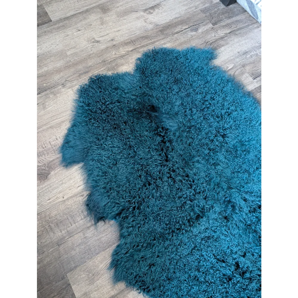 Soft curly dark teal Angus Oliver sheepskin rug on wood floor