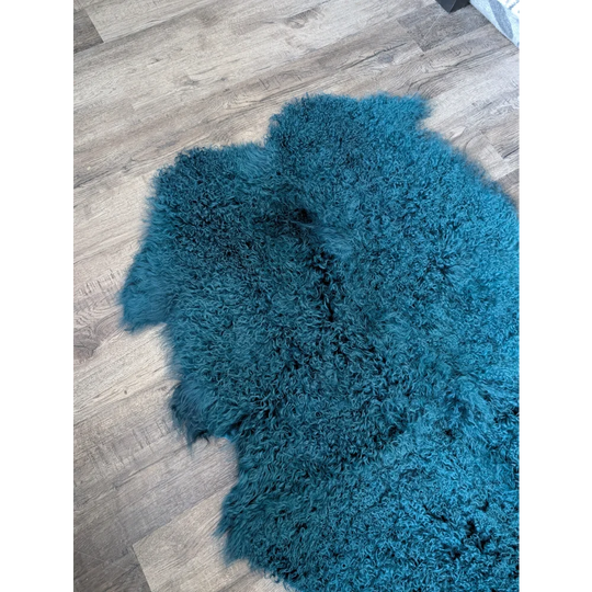 Soft curly dark teal Angus Oliver sheepskin rug on wood floor
