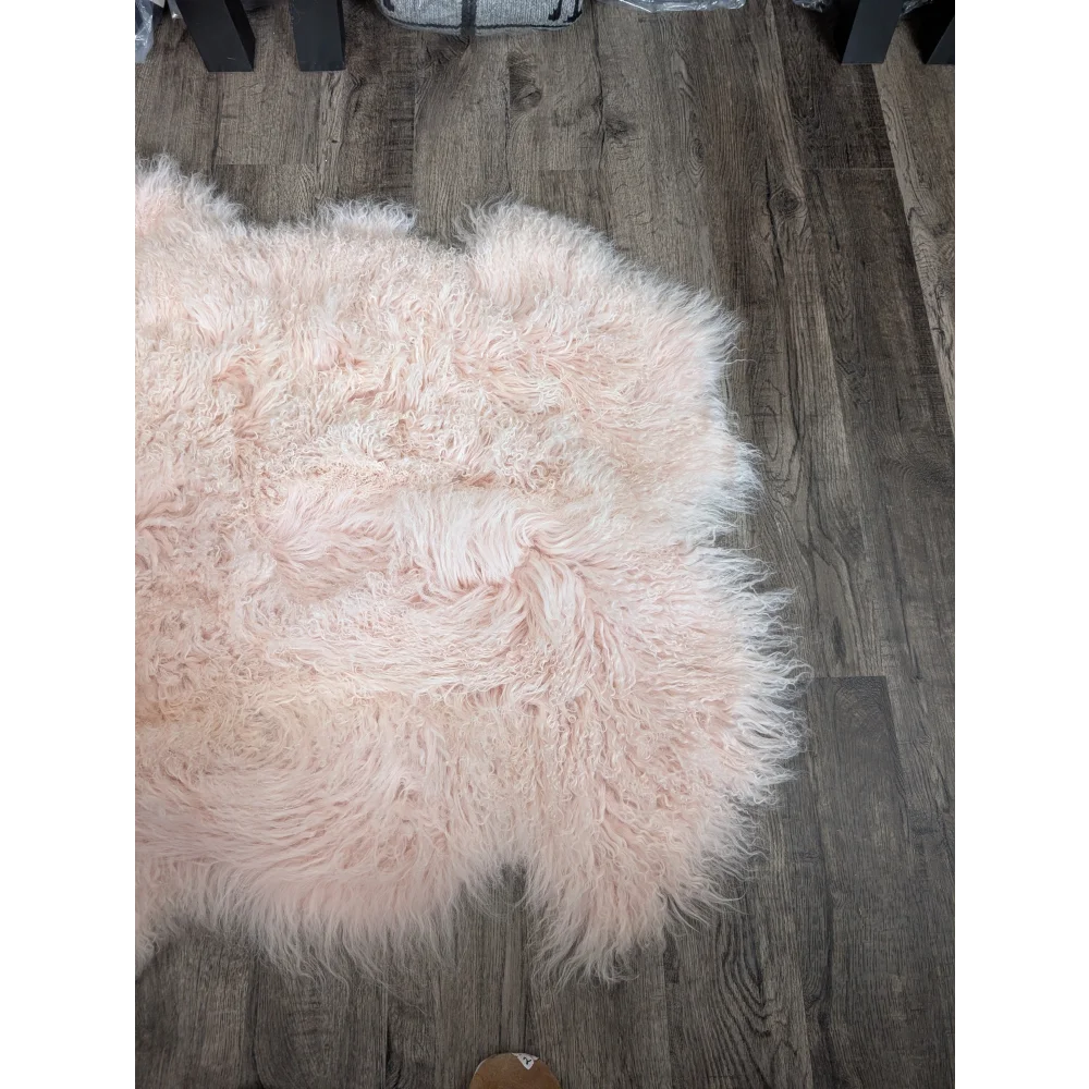 Blush pink 69x43 inch Angus Oliver sheepskin rug on dark wood floor