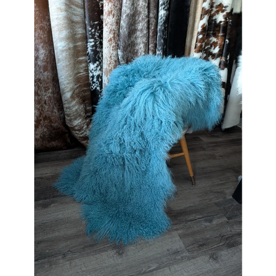 Vibrant turquoise 71x49 inch Mongolian sheepskin rug on wooden stool
