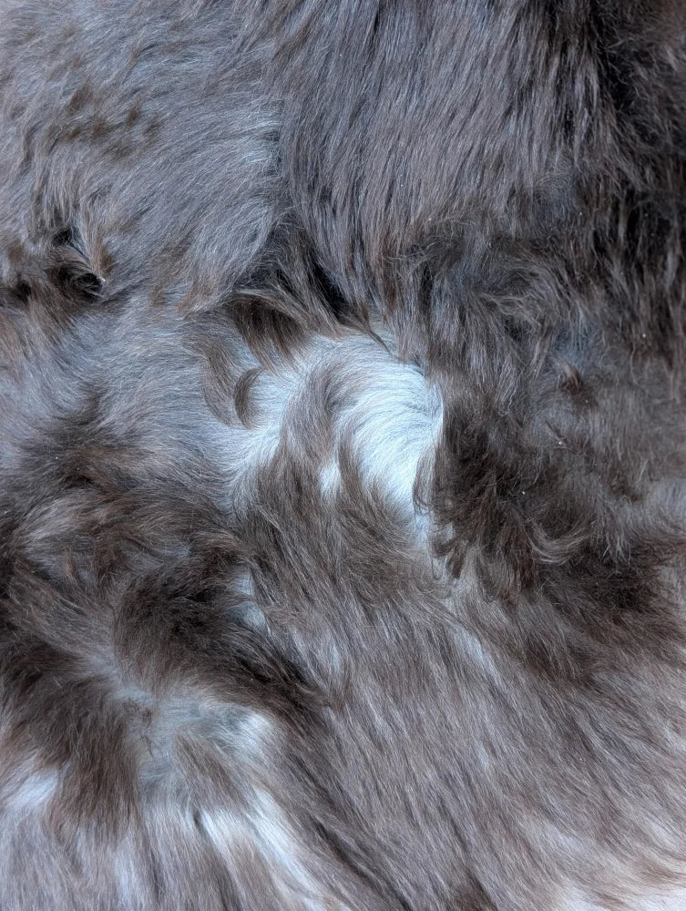 A plush dark gray british isles sheepskin rug with soft dense faux fur and subtle lighter gray and white patches