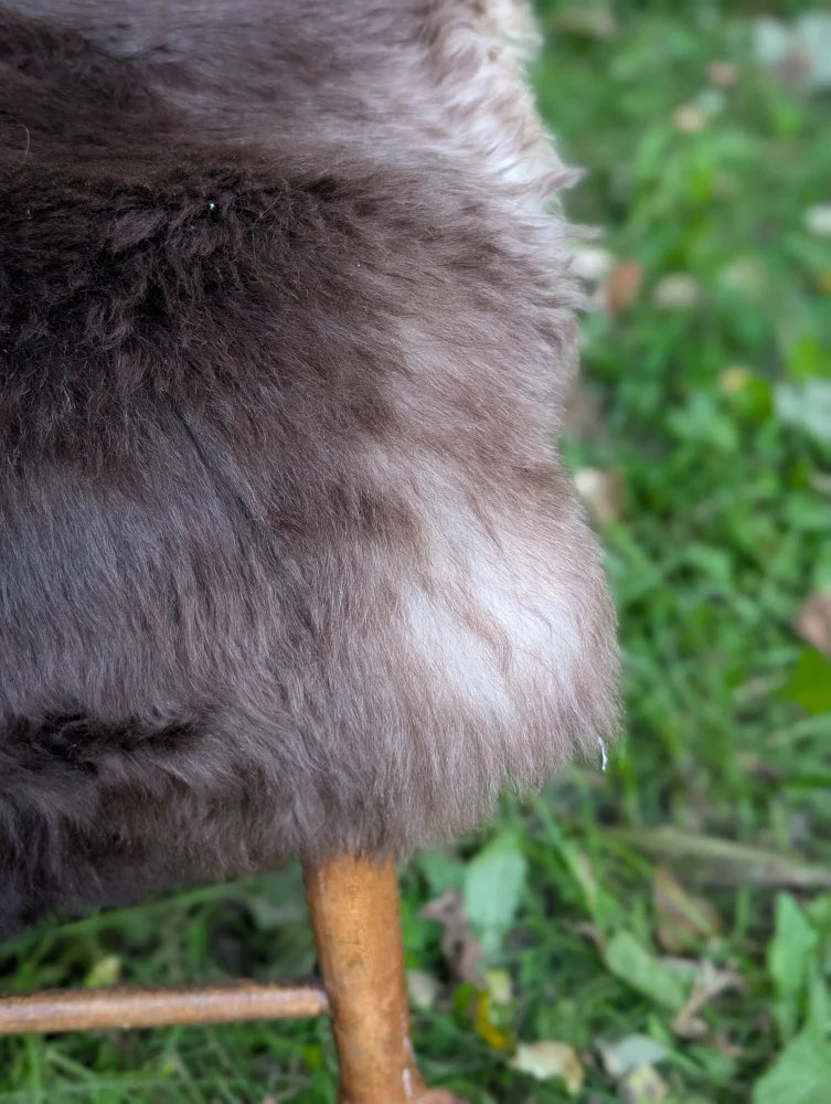 A plush dark gray british isles sheepskin coat with soft dense faux fur and subtle lighter patches near the hem