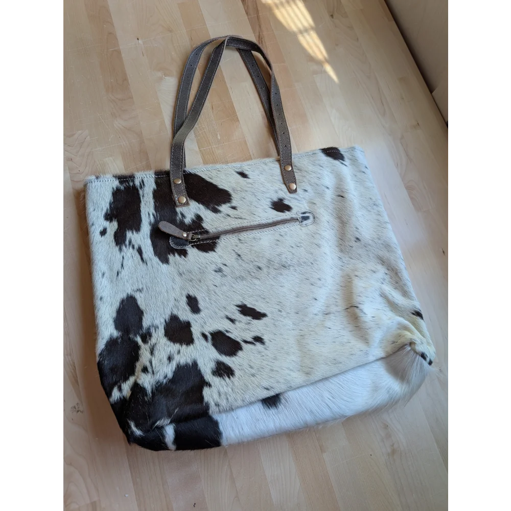 A white and black real cowhide tote bag with brown leather handles perfect for everyday use