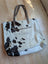 A white and black real cowhide tote bag with brown leather handles perfect for everyday use