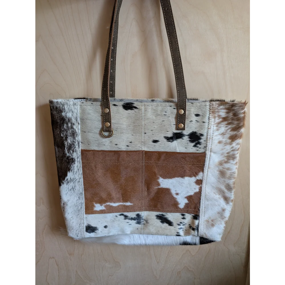 Brown and white real cowhide tote bag with leather straps perfect for carrying essentials in style