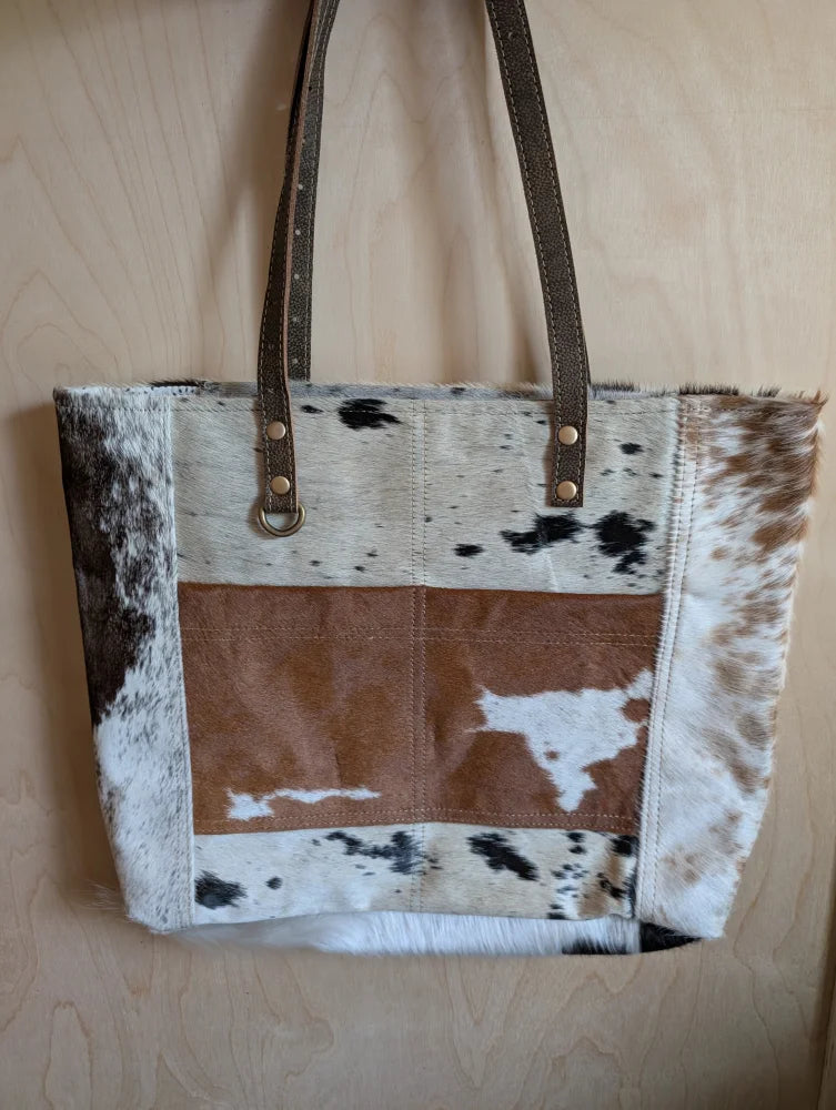 Brown and white real cowhide tote bag with leather straps perfect for carrying essentials in style