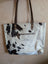 White and black real cowhide tote bag with brown leather straps perfect for carrying essentials like real cowhide rugs fans
