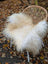 Cream-colored natural white icelandic sheepskin long wool throw draped over a wicker chair for cozy decor