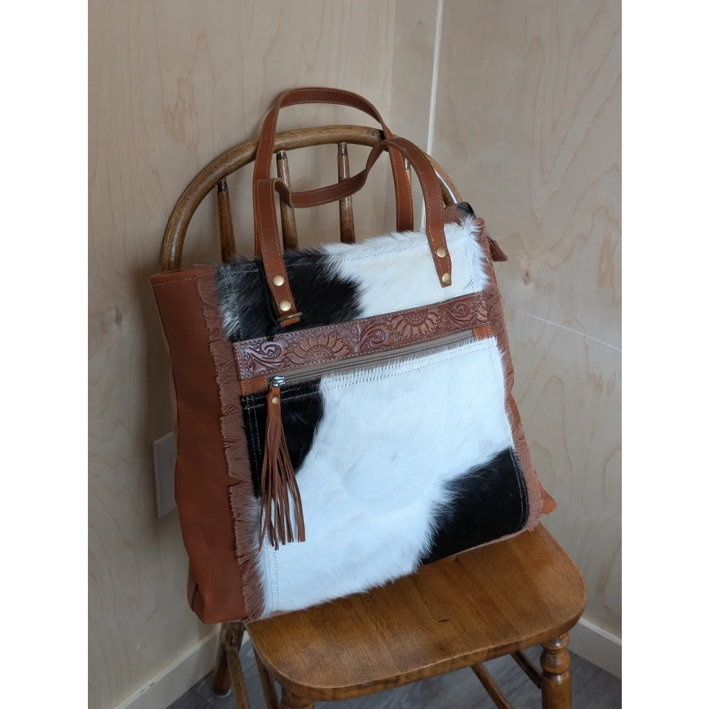 Brown and black real cowhide oakley specks canvas shoulder bag with tan trim, embossed zipper pull, and frayed edges