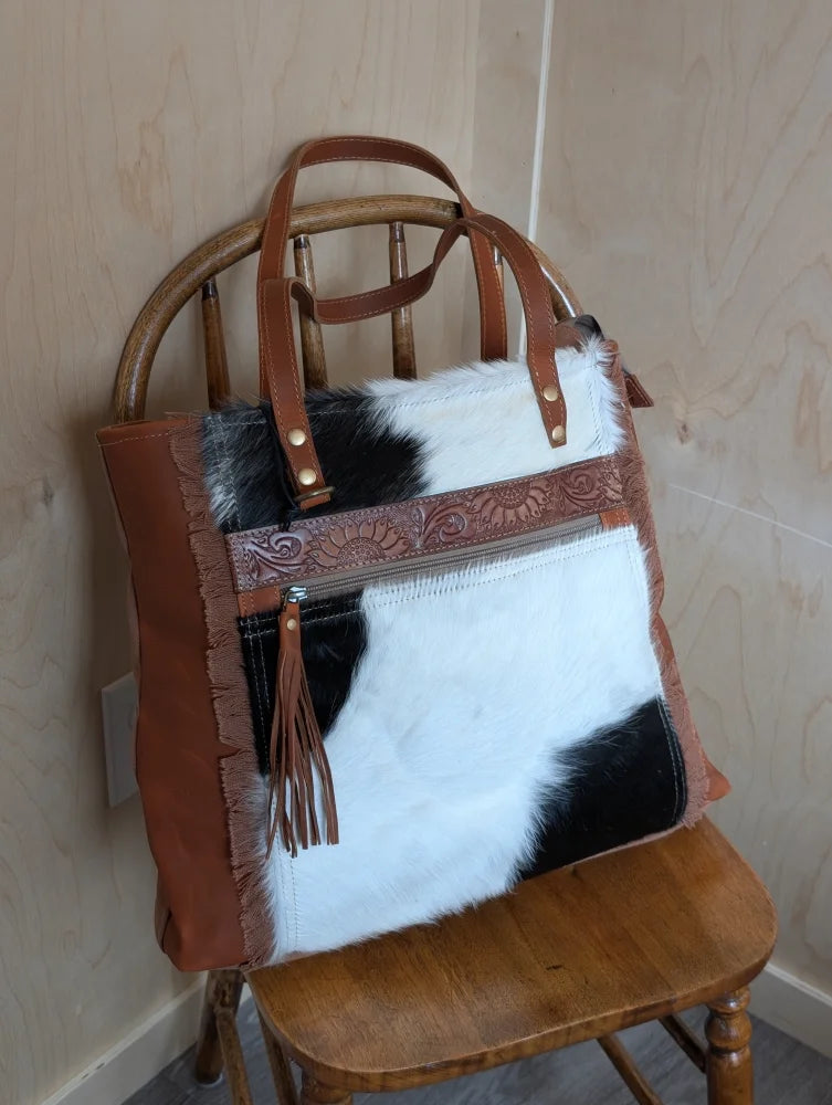 Brown and black real cowhide oakley specks canvas shoulder bag with tan trim, embossed zipper pull, and frayed edges
