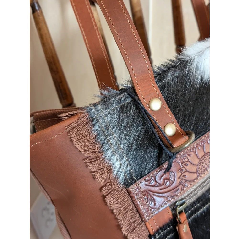 Brown leather oakley bag with real cowhide black and white trim, fringed detailing, and embossed floral zipper pull