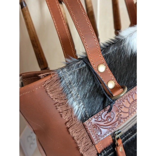 Brown leather oakley bag with real cowhide black and white trim, fringed detailing, and embossed floral zipper pull
