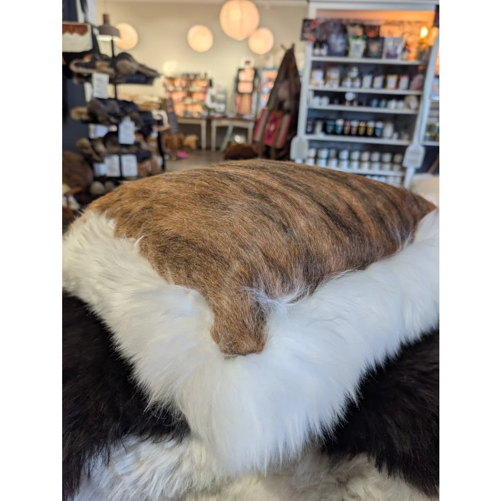 A plush brown and white merino sheepskin cushion by angus oliver canada with soft textured cowhide surface