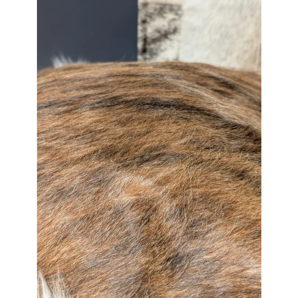 A close-up of a brown and black striped angus oliver cowhide merino sheepskin cushion from canada showing soft dense fur strands