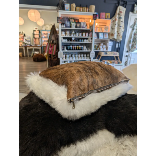 Brown and white cowhide pillow with plush white merino sheepskin trim by angus oliver canada