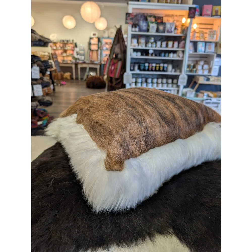Brown and white rectangular cushion made from merino sheepskin by angus oliver canada with unique cowhide design