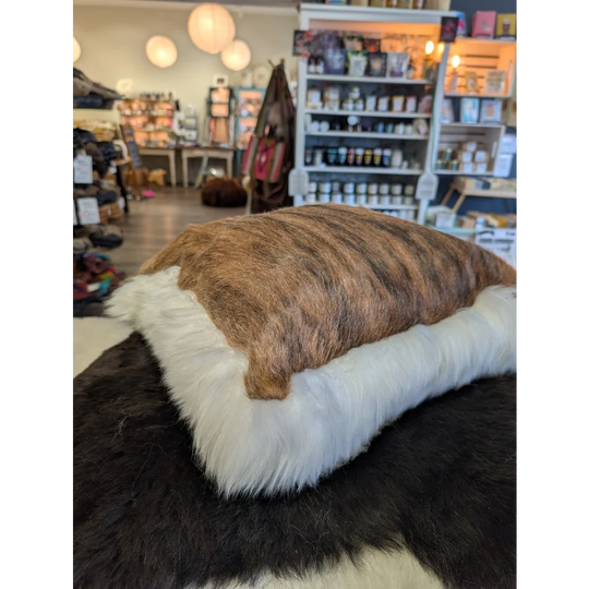 Brown and white rectangular cushion made from merino sheepskin by angus oliver canada with unique cowhide design
