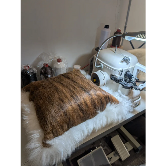 Brown faux fur pillow with plush white furry border made from merino sheepskin by angus oliver canada