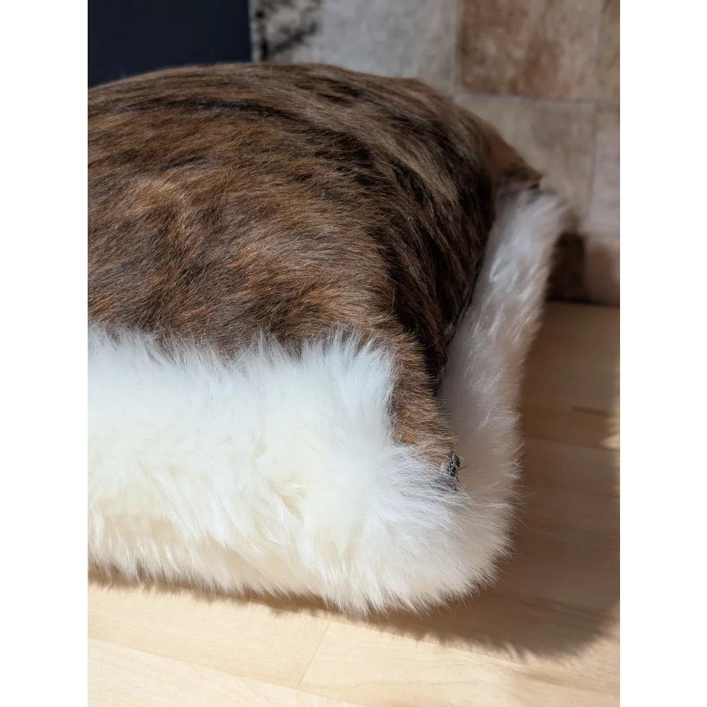 A plush rectangular cushion with brown and white merino sheepskin fur by angus oliver from canada