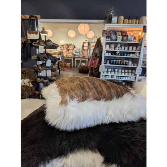 Brown and white fur-lined hat made from merino sheepskin by angus oliver canada matching one of a kind cushion