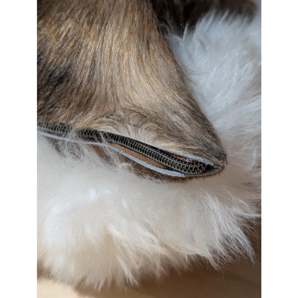 A close-up of a dark brown merino sheepskin zipper with fluffy fur lining on the angus oliver canada cowhide cushion