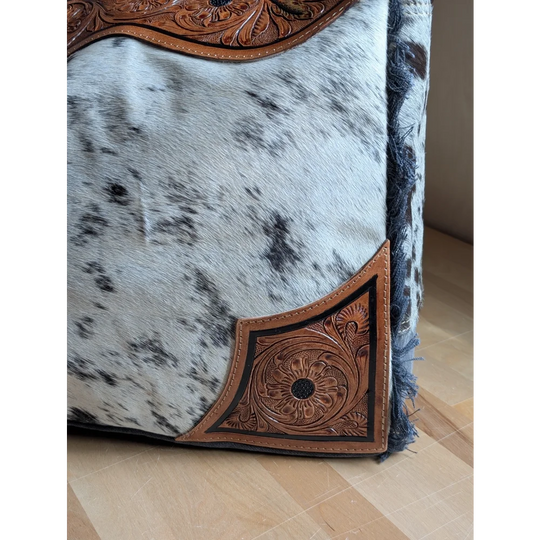 The sunflower weekender bag is a cartwright hand-tooled hair-on hide tote with intricate brown floral tooling and a zippered pocket