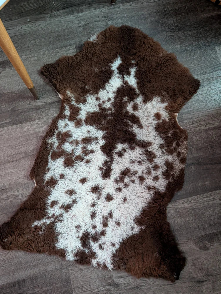 Brown and white highland spotted sheepskin grade a- rug with natural fluffy texture perfect for cozy decor