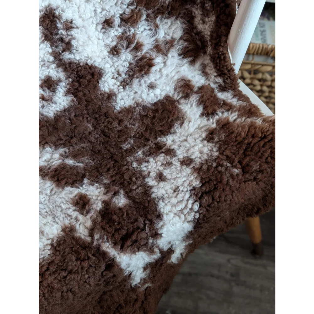 A cozy brown and white highland spotted grade a- sheepskin throw with soft plush texture perfect for warmth and decor
