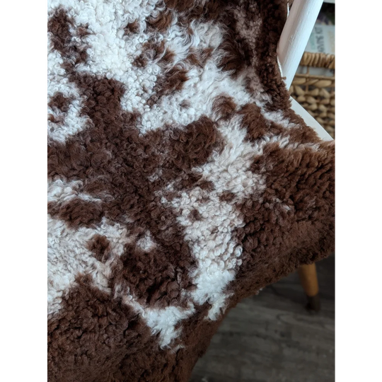 A cozy brown and white highland spotted grade a- sheepskin throw with soft plush texture perfect for warmth and decor