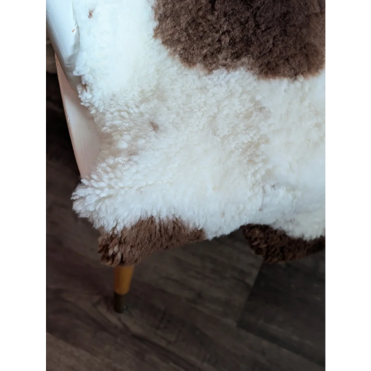 A cozy grade a- highland spotted sheepskin rug with fluffy white and brown fur texture perfect for home decor