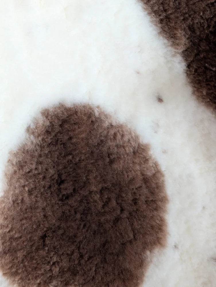 Brown fluffy highland spotted sheepskin patch on white background grade a- sheepskins detail