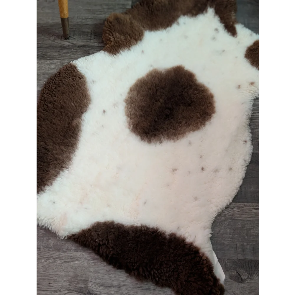 A plush grade a- sheepskin rug with a white and brown highland spotted cow print pattern