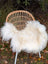 Large long wool natural white icelandic sheepskin throw draped over a woven wicker chair for cozy decor
