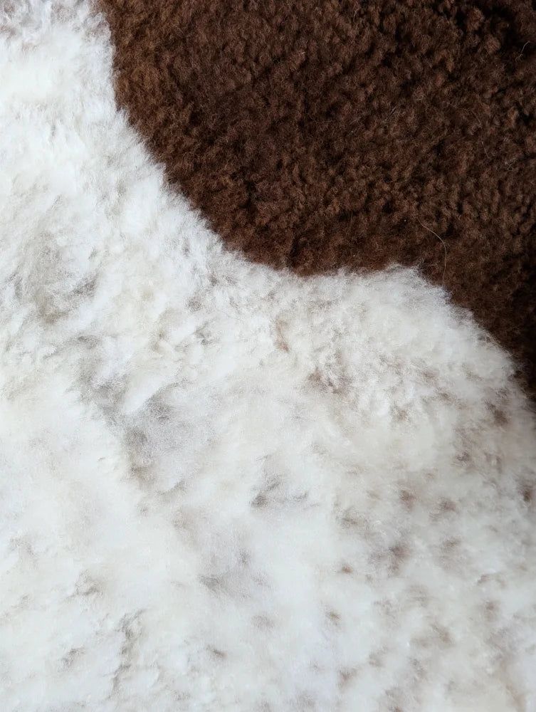 Brown and white fluffy cozy knit fabric of grade a- highland spotted sheepskin for warm comfortable use