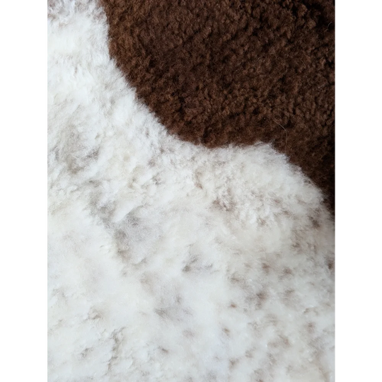 Brown and white fluffy cozy knit fabric of grade a- highland spotted sheepskin for warm comfortable use