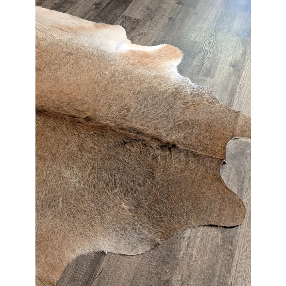 Tan and white extra large cowhide rug with natural fur texture adding rustic charm to wooden floor beautiful rugs