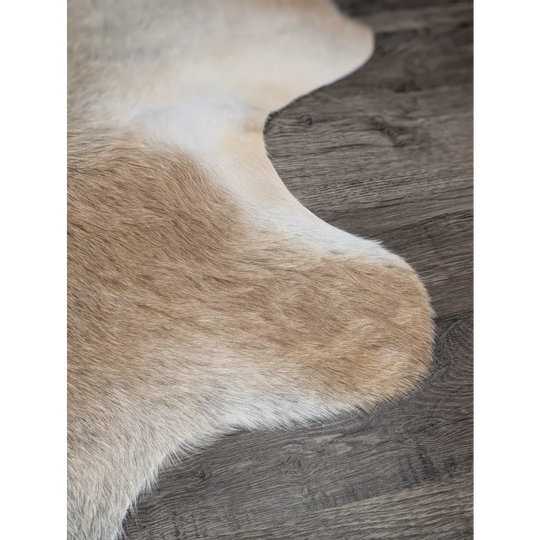 A beautiful extra large cowhide rug in creamy white and warm tan tones adding rustic charm to any space