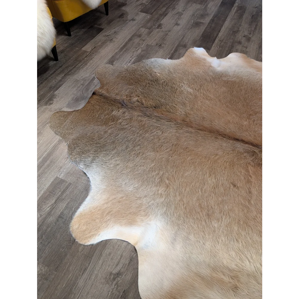 A beautiful extra large cowhide rug in natural tan and white with soft fluffy texture adding rustic charm to any room