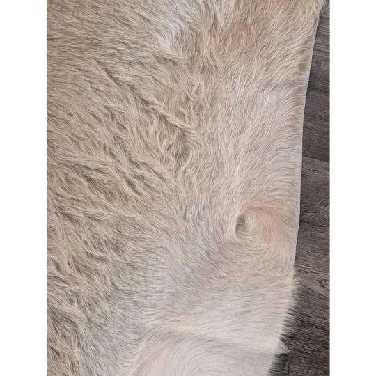 A beautiful extra large cowhide rug in natural beige with plush texture and subtle shade variations for rustic charm