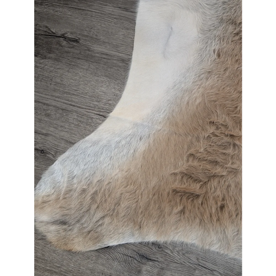 A soft extra large cowhide rug with natural creamy white and light brown tones perfect for rustic charm spaces