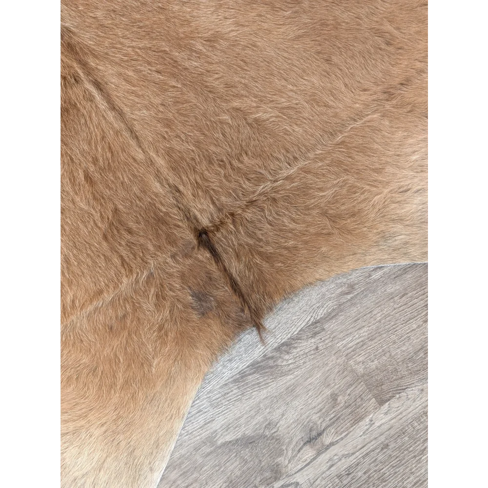 Tan faux fur extra large cowhide rug with soft plush texture and visible stitching perfect for rustic charm beautiful rugs