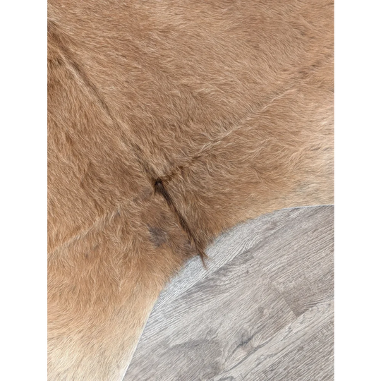 Tan faux fur extra large cowhide rug with soft plush texture and visible stitching perfect for rustic charm beautiful rugs