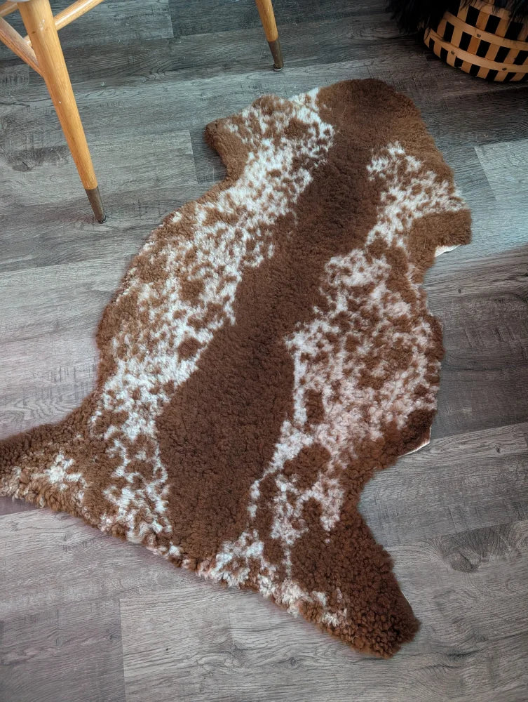 Brown and white speckled highland spotted grade b sheepskin rug with plush textured surface