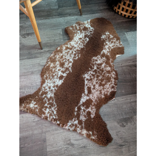 Brown and white speckled highland spotted grade b sheepskin rug with plush textured surface
