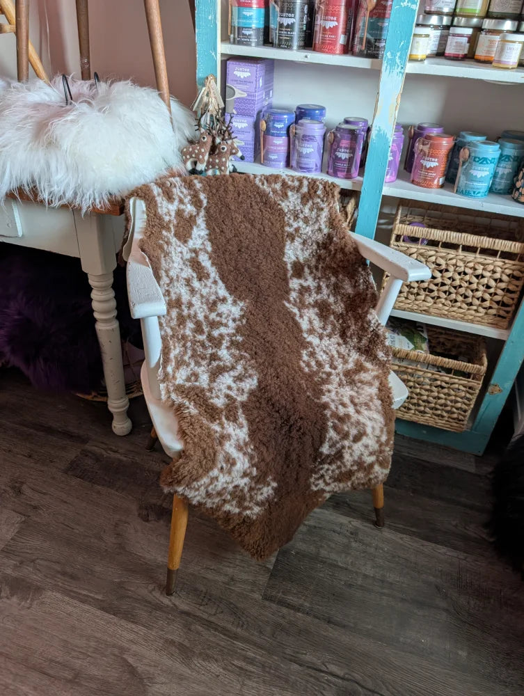 Brown and white highland spotted grade b sheepskin throw draped over chair perfect for cozy decor and sheepskin rugs