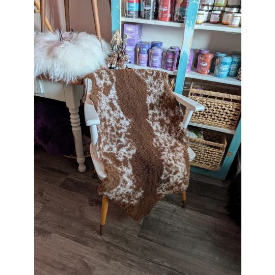 Brown and white highland spotted grade b sheepskin throw draped over chair perfect for cozy decor and sheepskin rugs