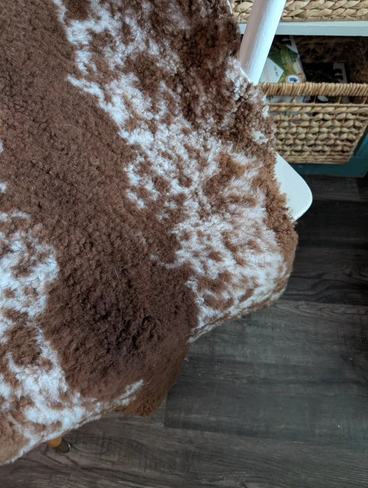 Brown and white fluffy highland spotted grade b sheepskin rug with natural textured surface perfect for cozy decor